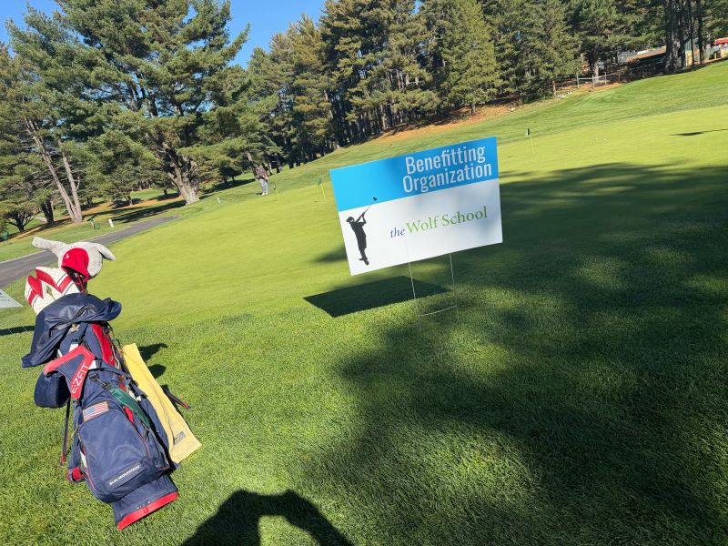 A Kev Classic sign naming The Wolf School as the benefitting organization, on the course at Needham Golf Club